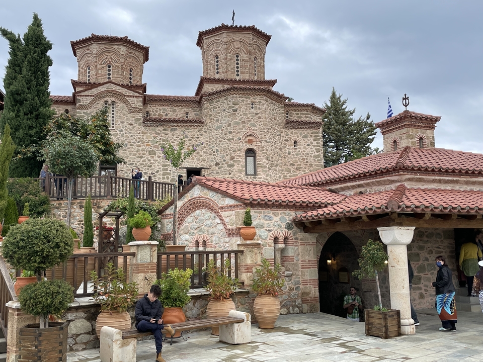 Bâtiment en pierre avec tour et des gens autour.