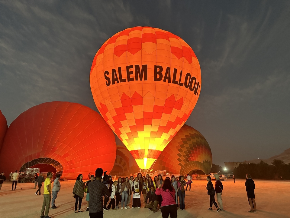 Group of people standing near large hot air balloons during inflation.