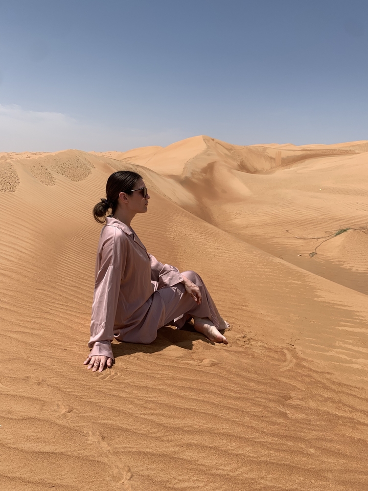 Personne assise sur des dunes de sable dans un désert.