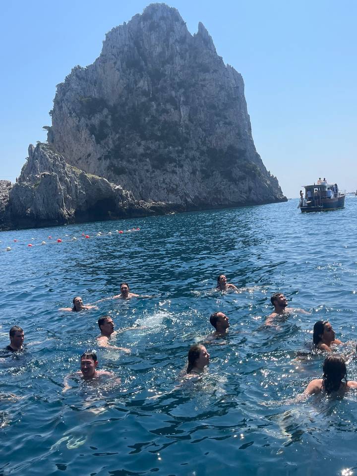 Groupe de personnes nageant dans l'océan avec une falaise.