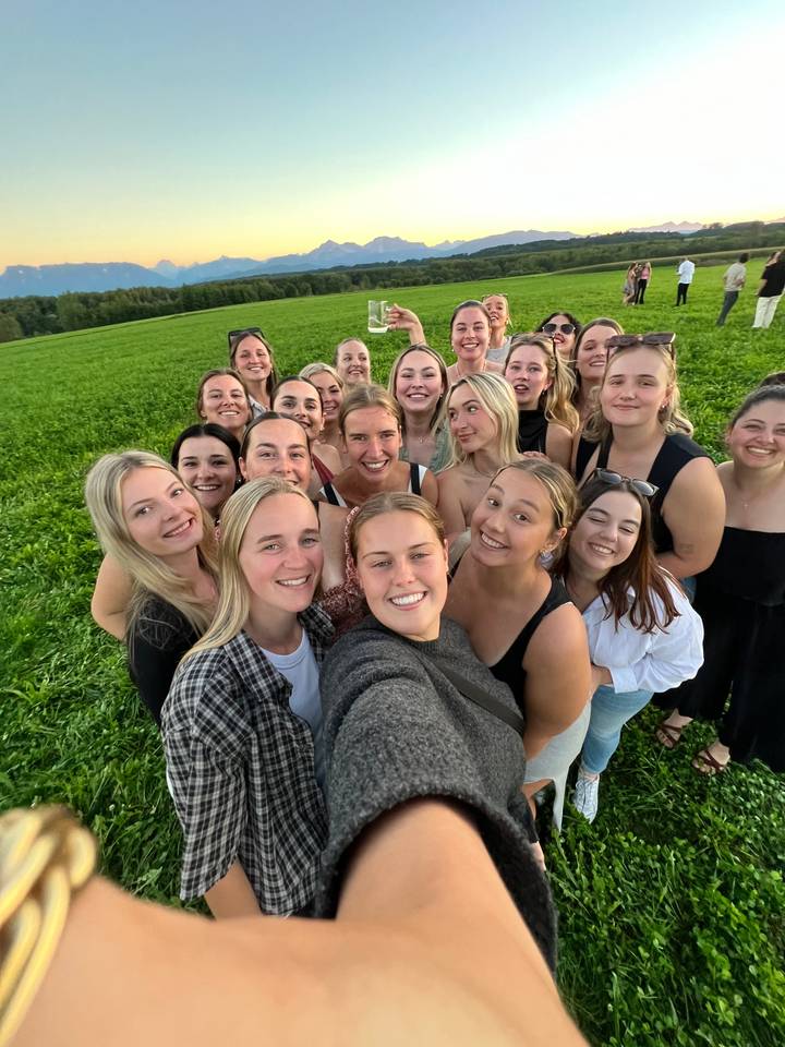 Un grand groupe de personnes prenant un selfie dans un champ vert.
