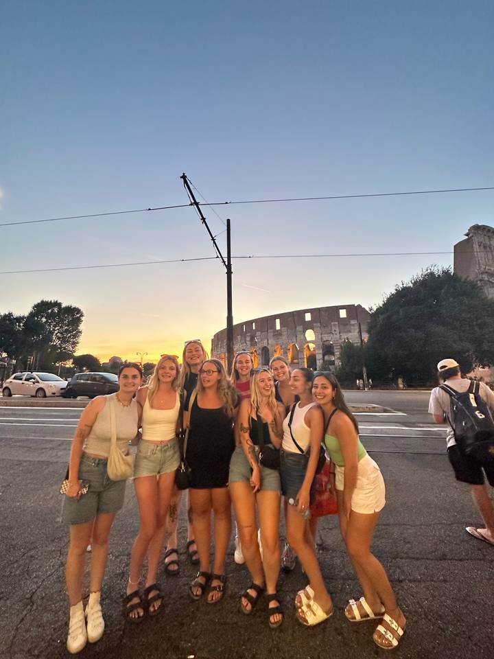 Un groupe de personnes posant dans une rue avec une vue sur le coucher de soleil.