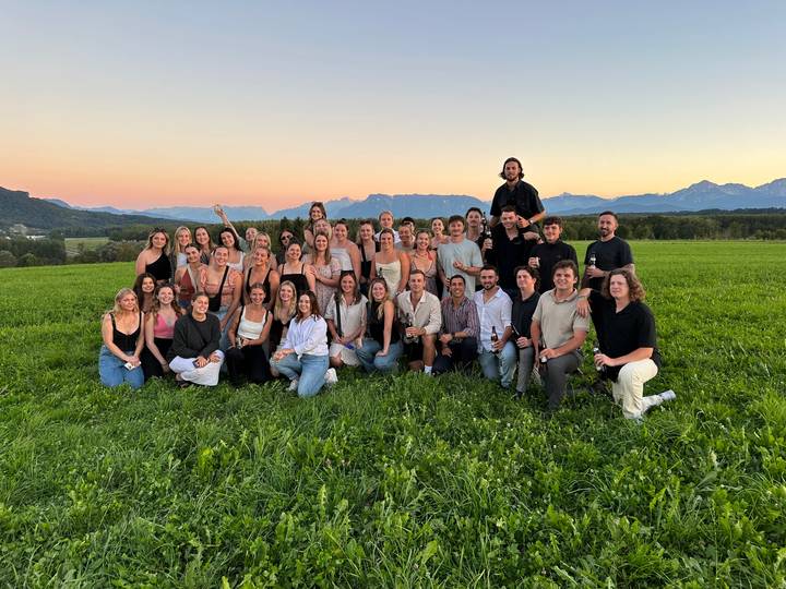 Un grand groupe de personnes rassemblées dans un champ avec une montagne en toile de fond.