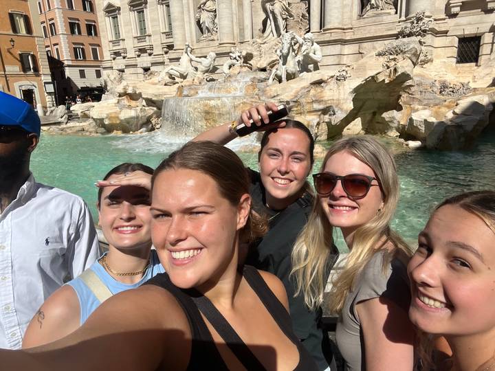 Un groupe de personnes posant devant une fontaine.