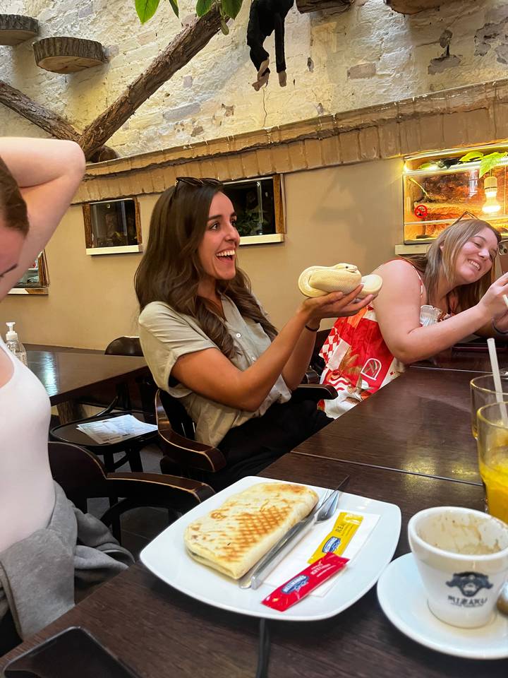 Femme souriante avec une pâtisserie à une table.
