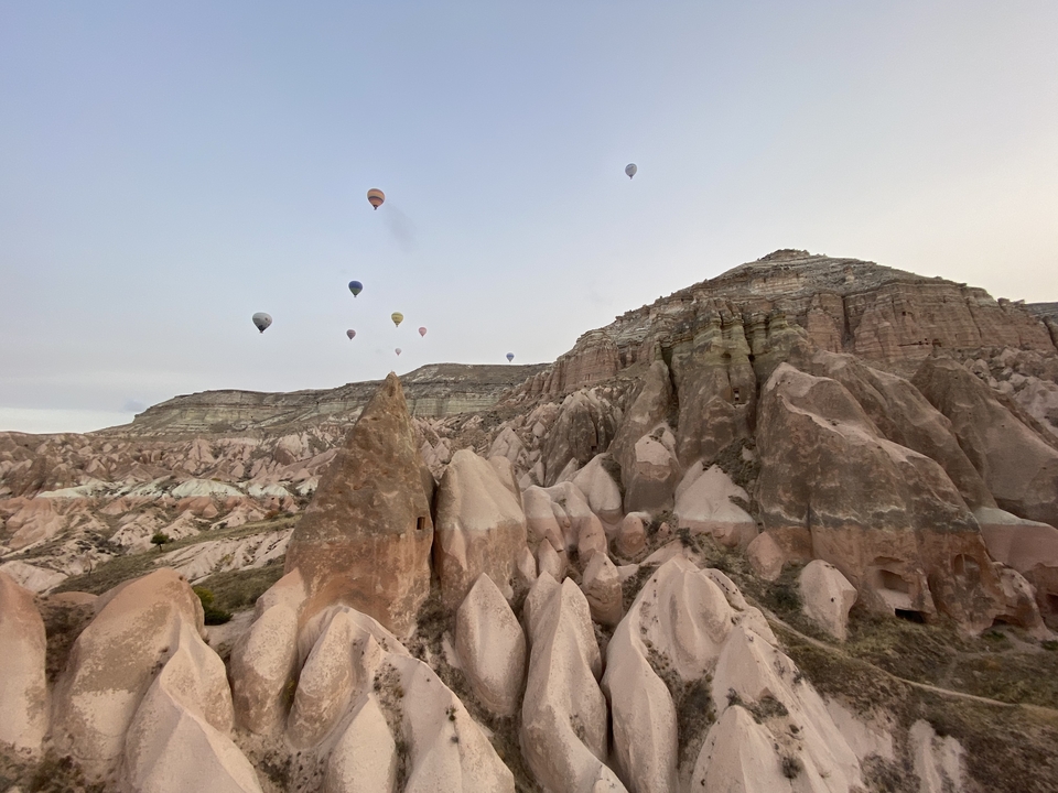 Des montgolfières flottant au-dessus d'un paysage rocheux.