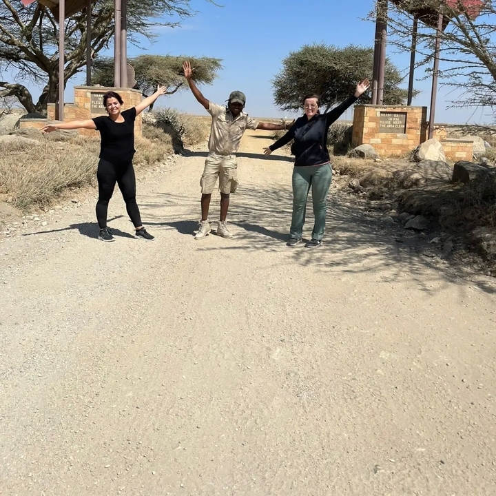 Trois personnes les bras écartés sur un chemin de terre.