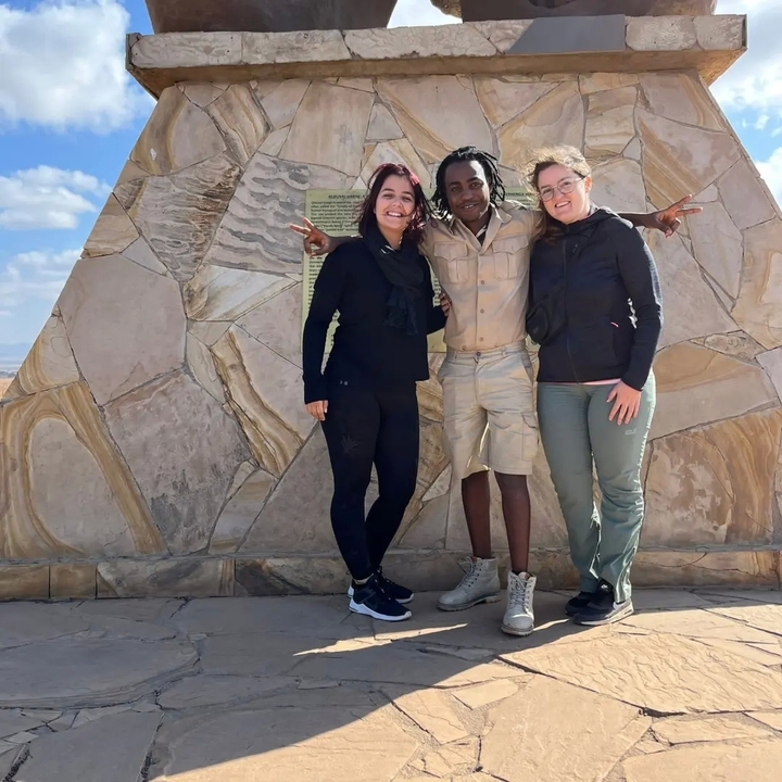 Trois personnes posant devant un monument en pierre.