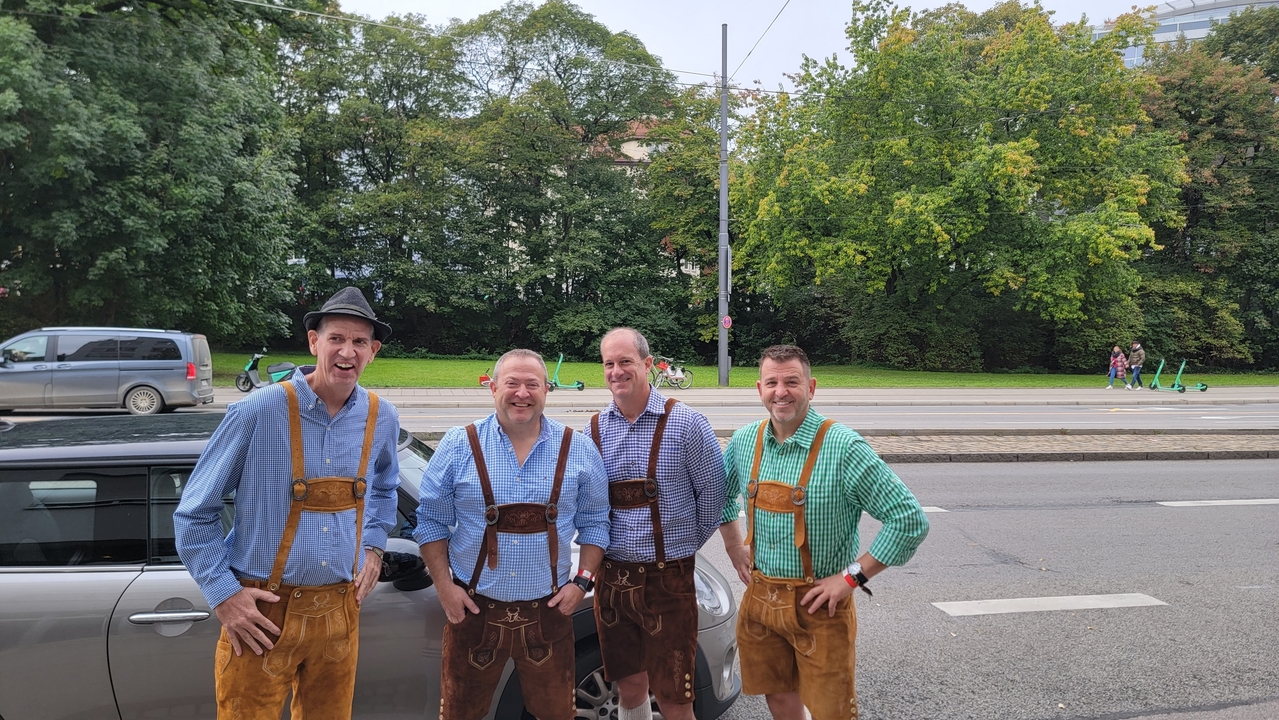 Quatre hommes en vêtements traditionnels bavarois à l'extérieur.