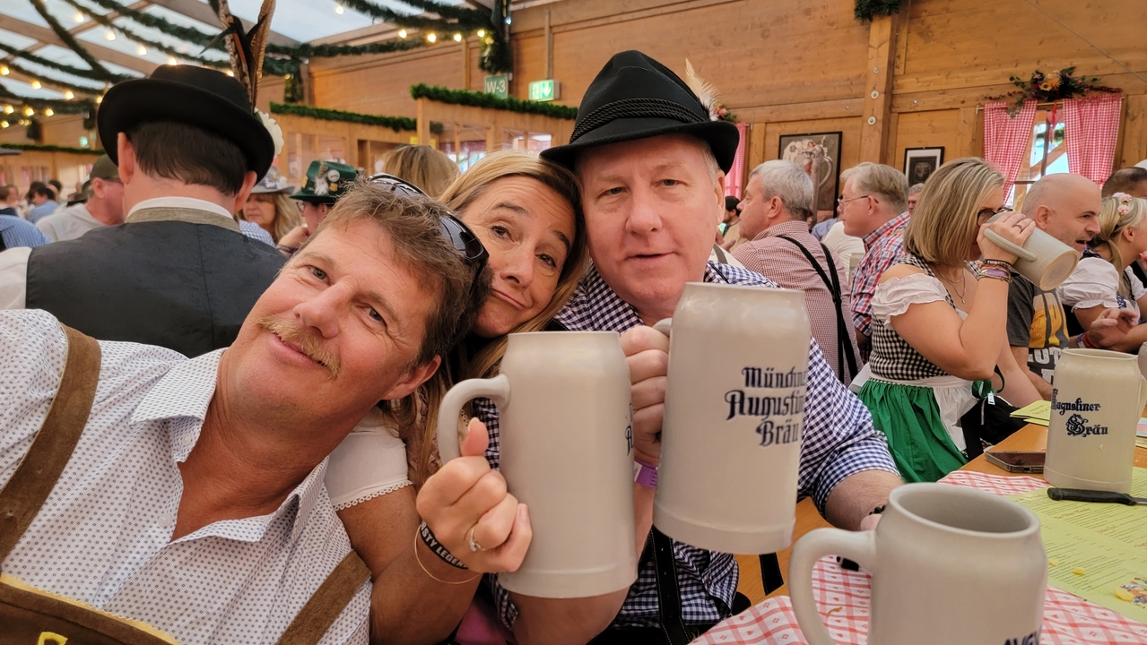 Trois personnes en vêtements bavarois traditionnels tenant des chopes de bière.