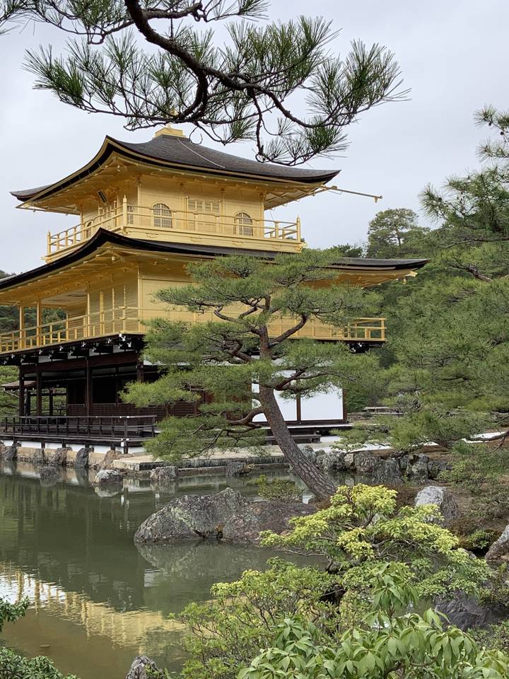 Pavillon doré entouré d'arbres et d'un étang.