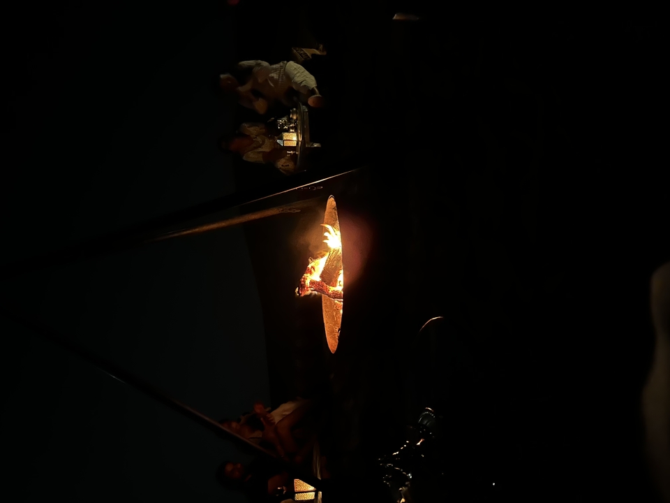 Un feu de camp dans l'obscurité avec des gens assis autour.