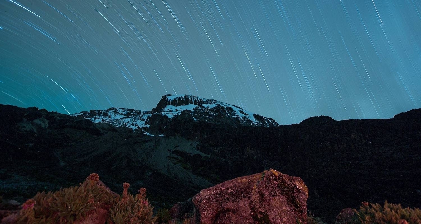 Montagne sous un ciel étoilé avec des traînées d'étoiles.