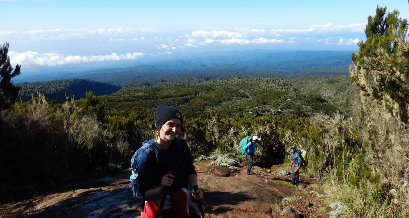 Randonneur souriant avec des montagnes en arrière-plan.