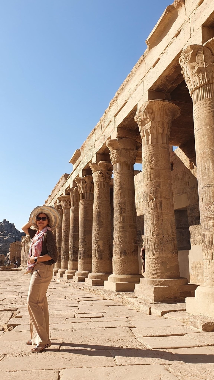 Femme posant près de colonnes de temple antique.