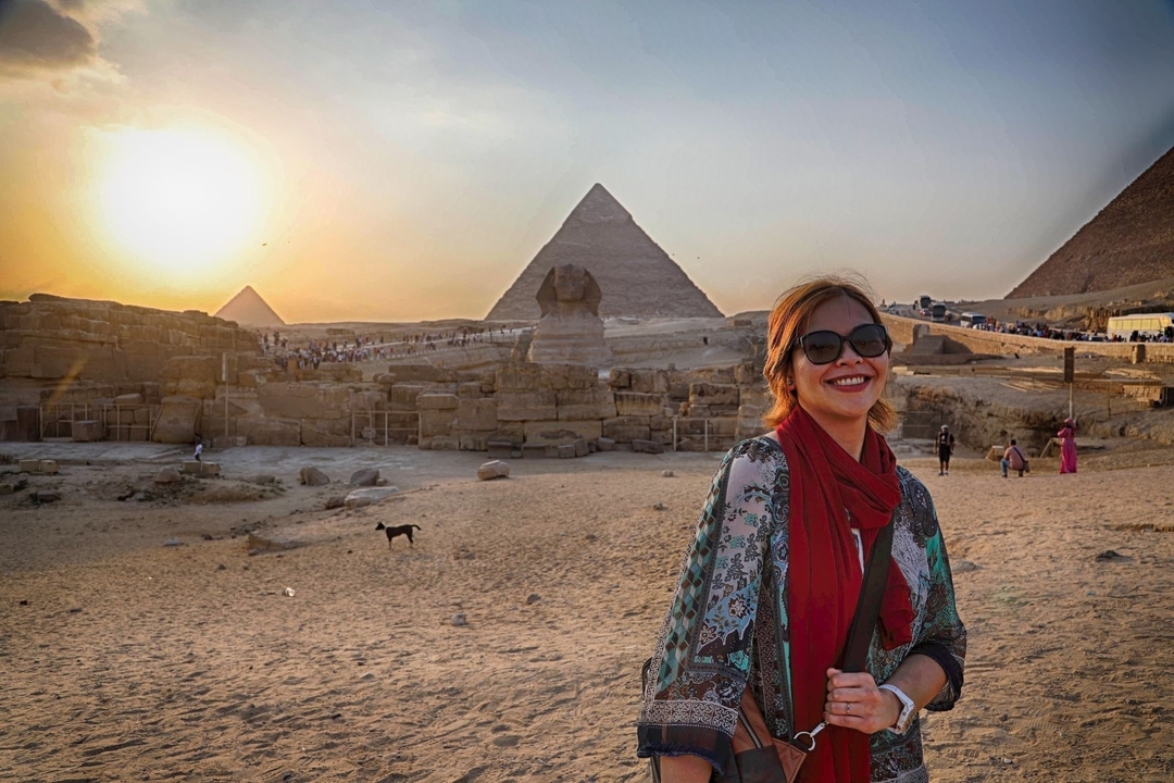 Femme posant avec les pyramides et le Sphinx au coucher du soleil.