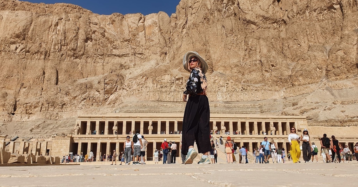 Des personnes devant le temple d'Hatchepsout en Égypte avec une falaise en arrière-plan.