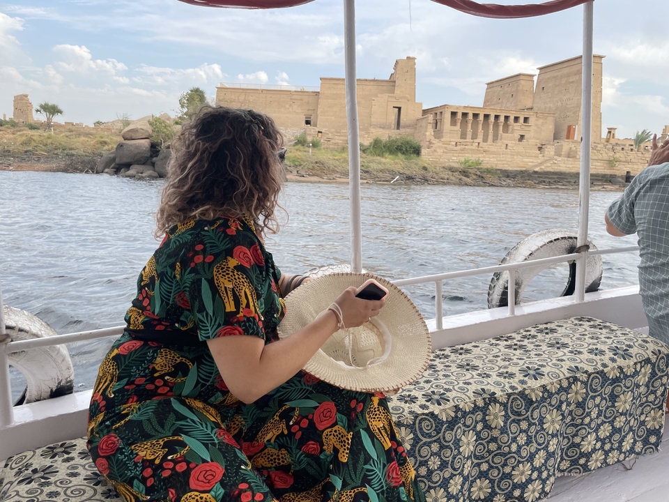 Personne assise sur un bateau avec des ruines de temple en arrière-plan.