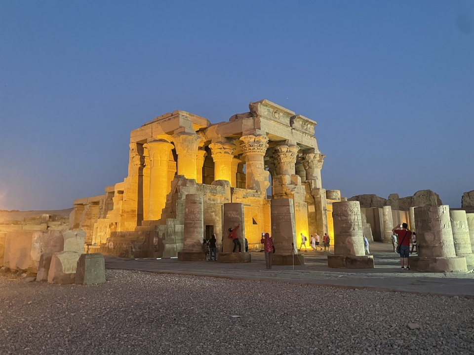 Temple antique illuminé avec des gens autour.
