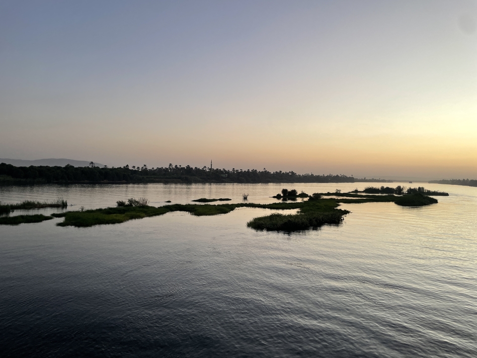 Vue panoramique d'une rivière au coucher du soleil avec des reflets.
