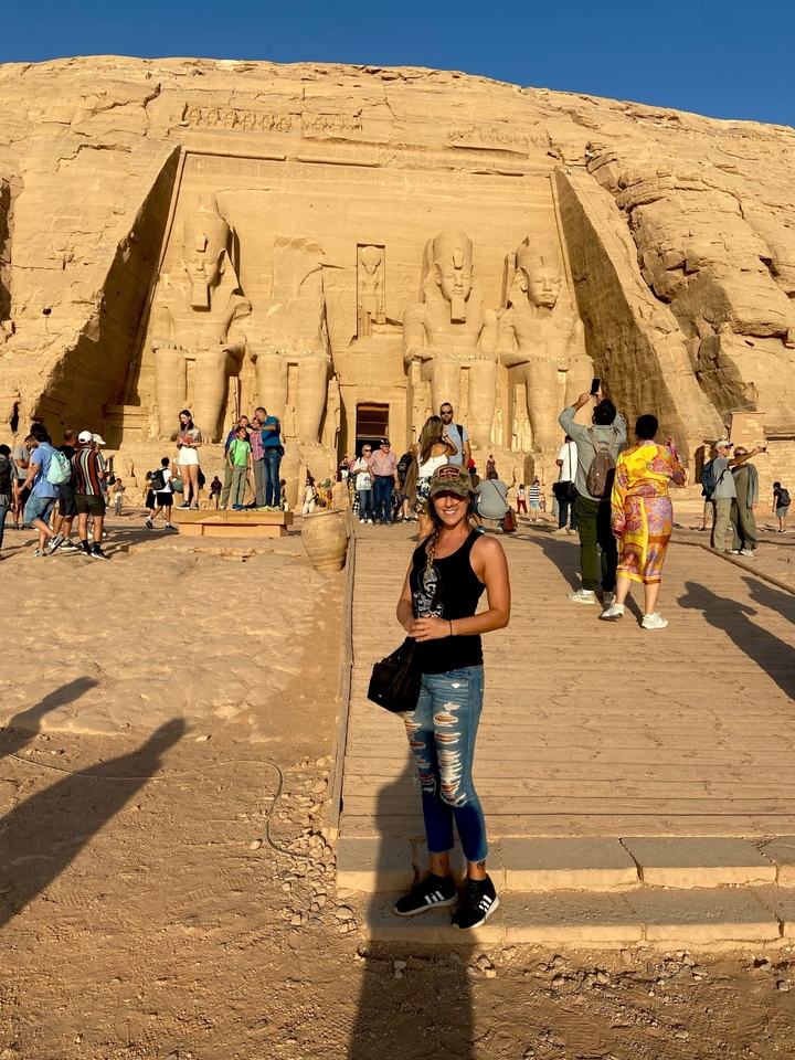 Des gens à l'entrée d'Abou Simbel avec des statues sculptées dans la roche.
