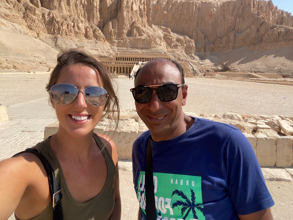 Deux personnes prenant un selfie avec le temple d'Hatchepsout en arrière-plan.
