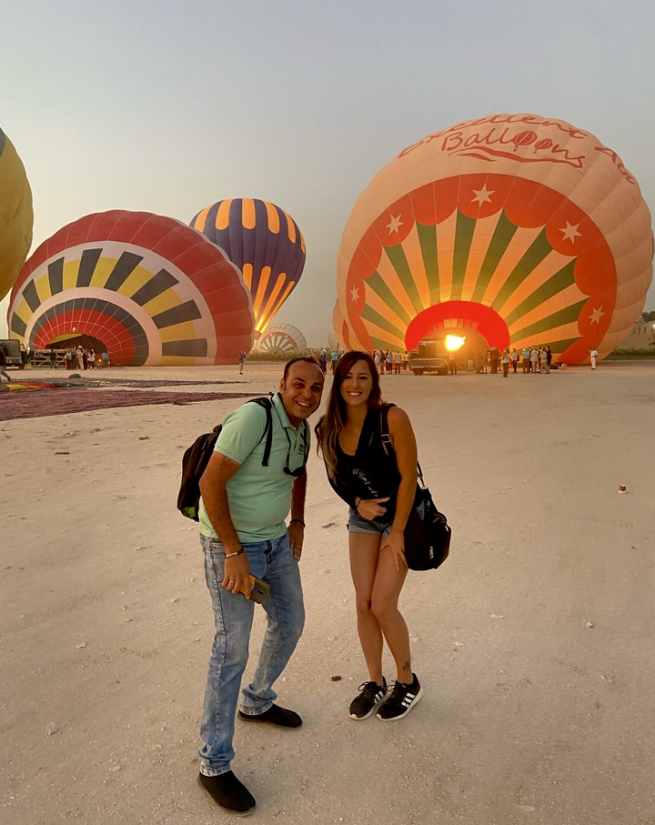 Deux personnes posant devant des montgolfières gonflées.