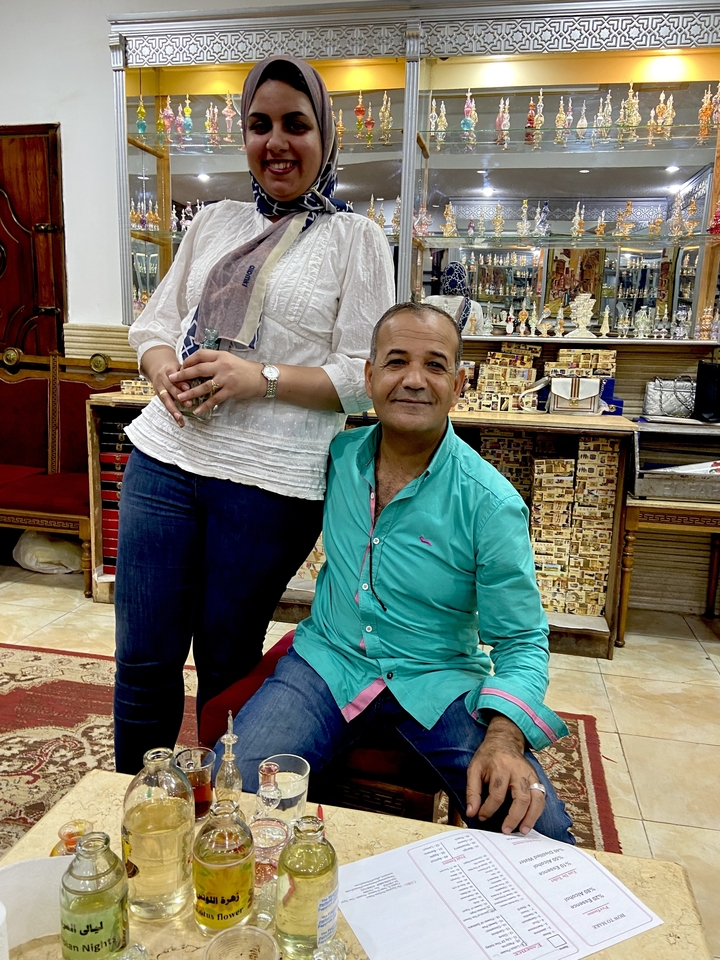 Homme et femme souriants devant un magasin de souvenirs.