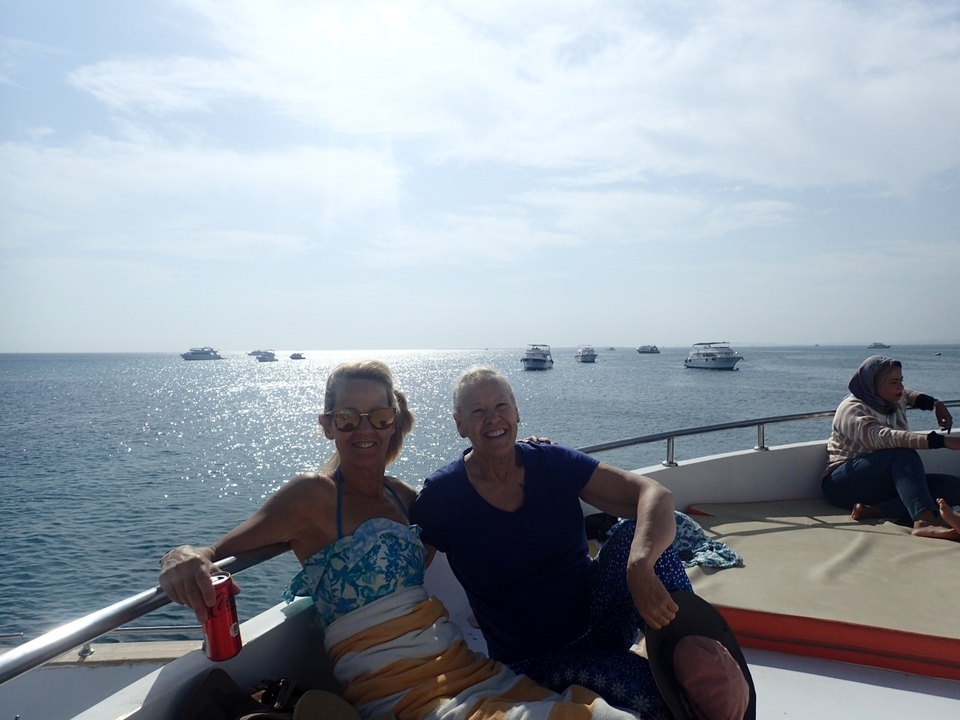 Deux femmes assises sur un bateau avec d'autres bateaux au loin par une journée ensoleillée.