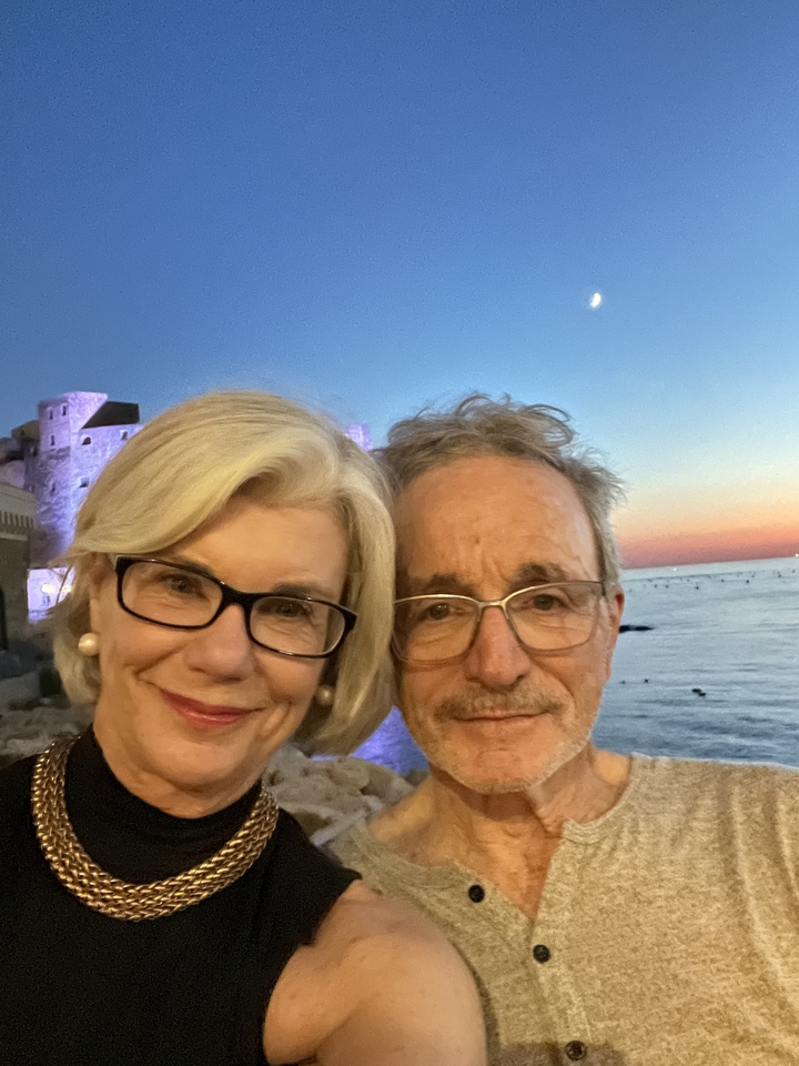 Couple prenant un selfie avec un front de mer et un château en arrière-plan.