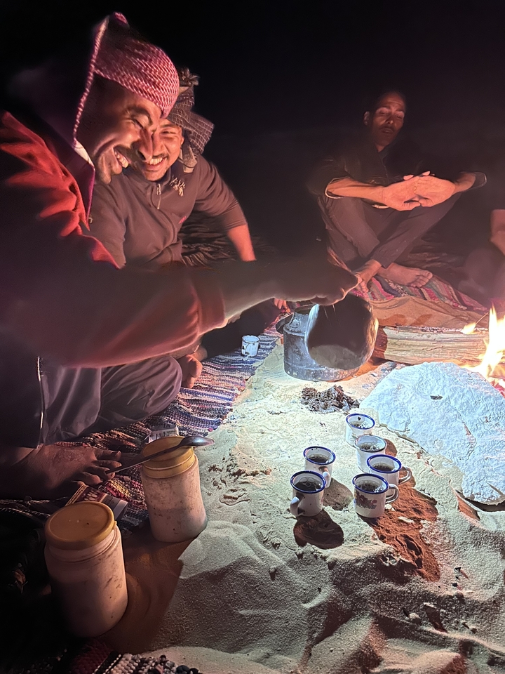 Groupe de personnes prenant le thé autour d'un feu de camp la nuit.