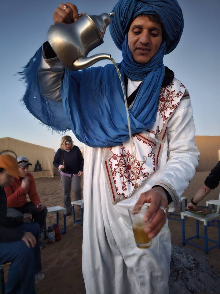 Homme versant du thé en tenue traditionnelle.