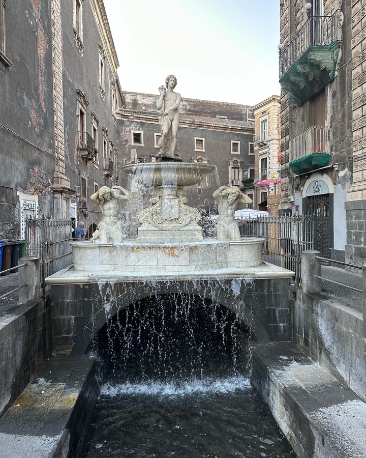 Une fontaine décorative avec des sculptures sur une place historique.