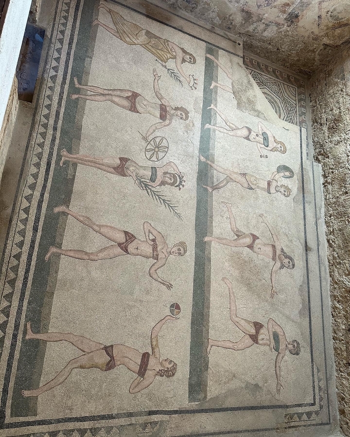 Sol en mosaïque antique avec des athlètes pratiquant diverses activités.