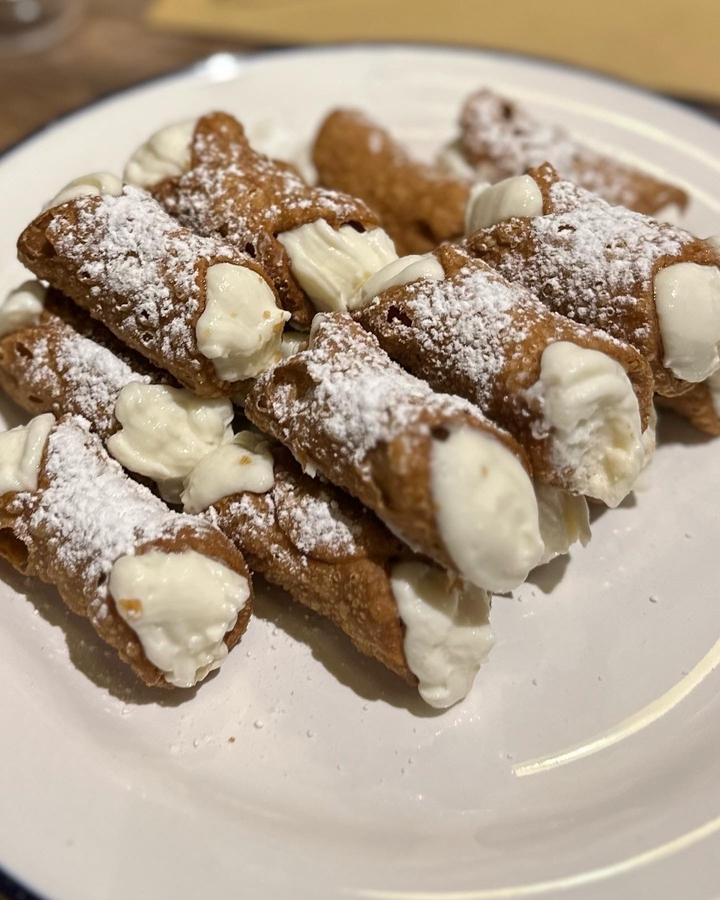 Une assiette de cannoli italiens traditionnels saupoudrés de sucre.
