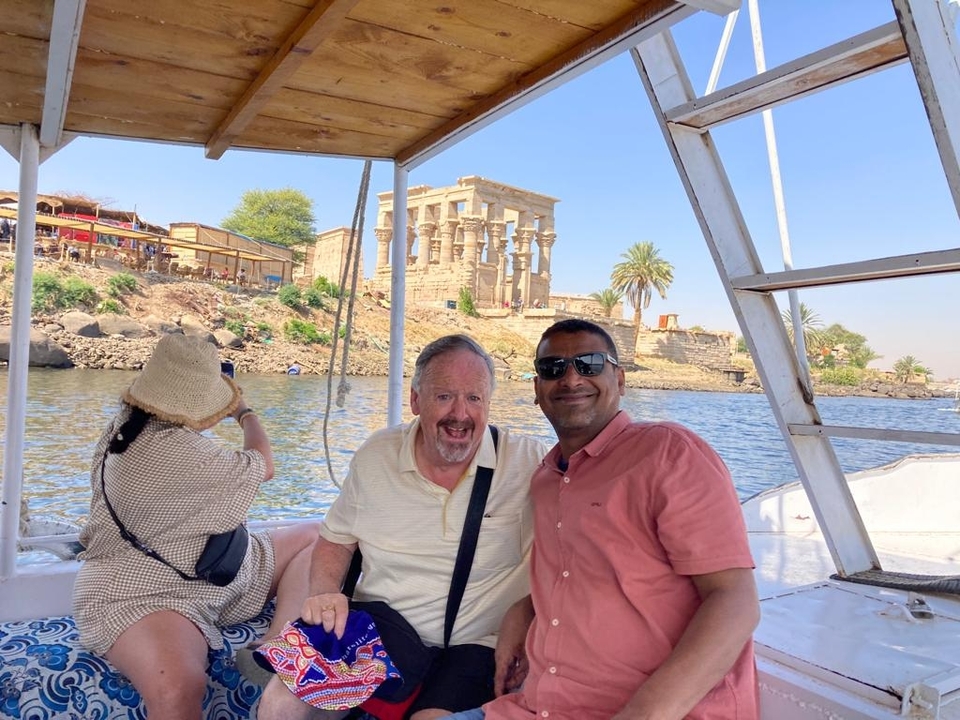 Des gens sur un bateau avec des ruines antiques en arrière-plan.