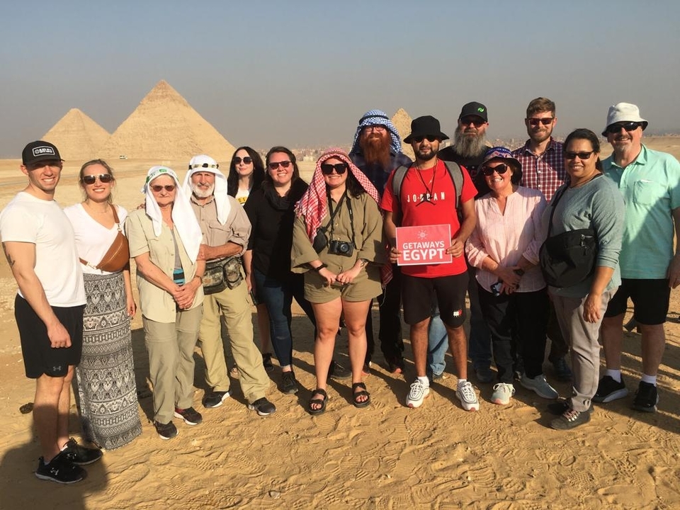 Groupe de touristes posant devant les pyramides.