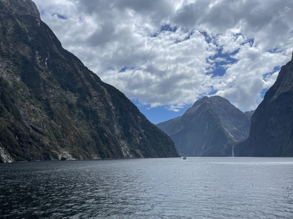 Fjord with steep cliffs and a boat on the water.