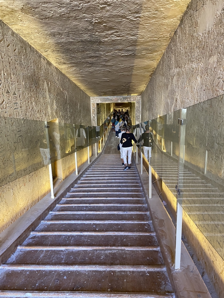 Des personnes marchant à travers un passage en pierre ancienne avec des hiéroglyphes.