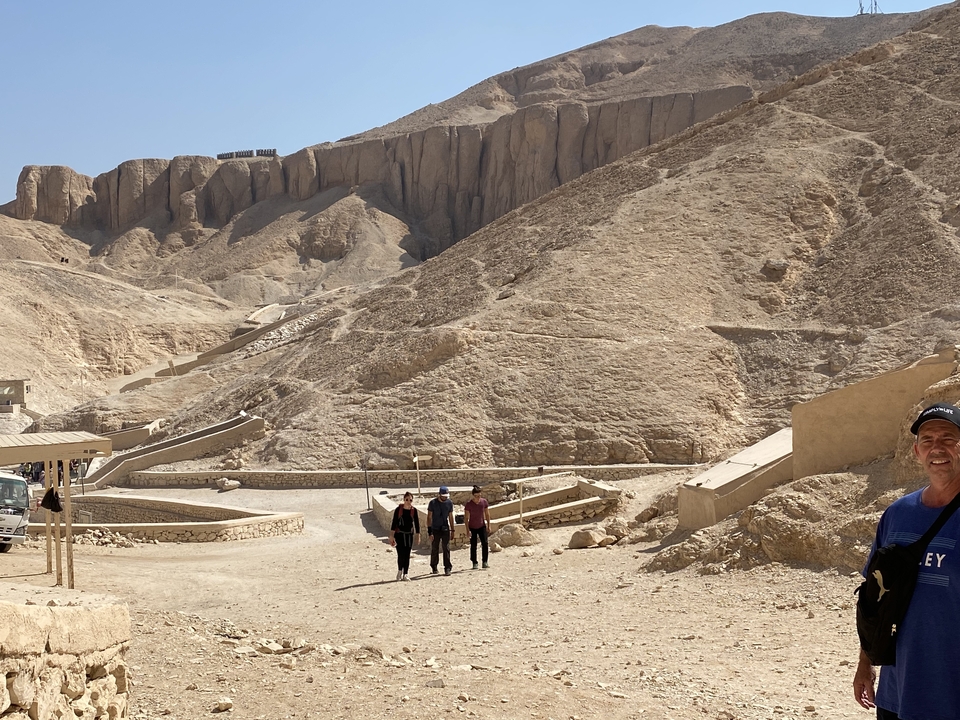 Des touristes marchant à travers un paysage désertique avec des collines rocheuses.