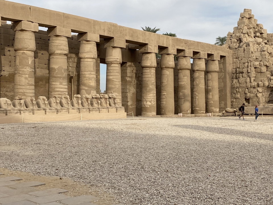 Une rangée de statues et de colonnes dans un temple égyptien antique.
