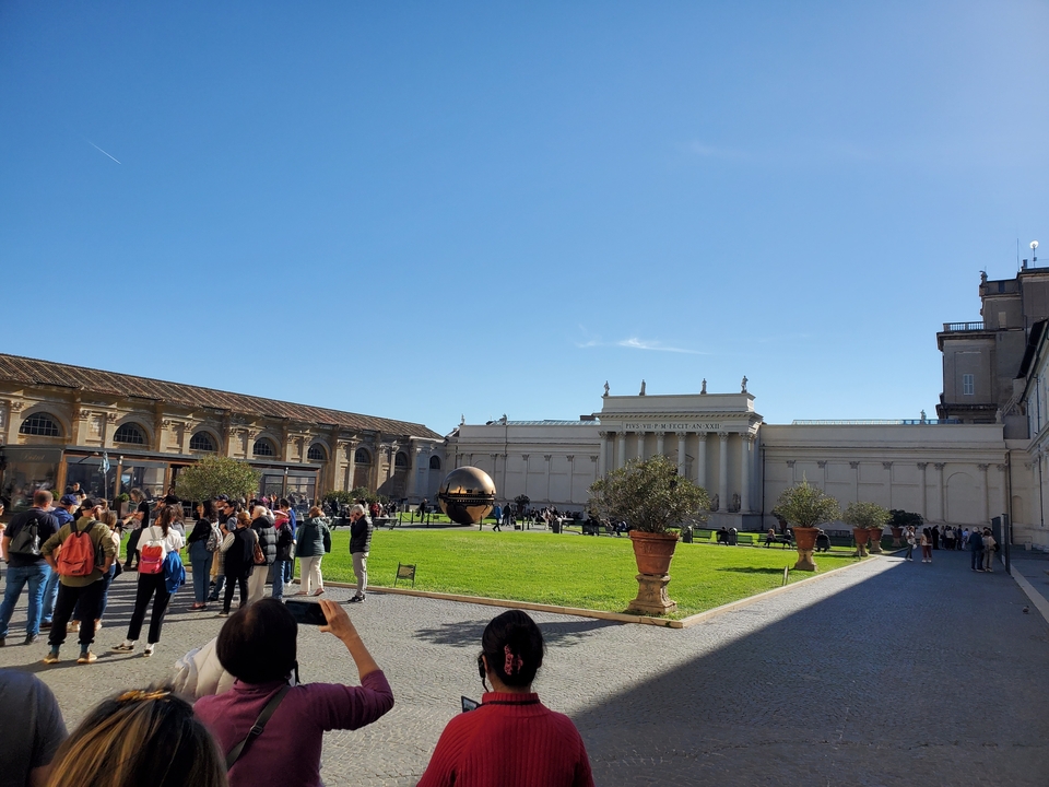 Foules devant les Musées du Vatican avec la sculpture sphérique.