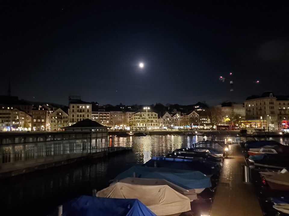 Vue nocturne d'un port de ville avec des bateaux et clair de lune.