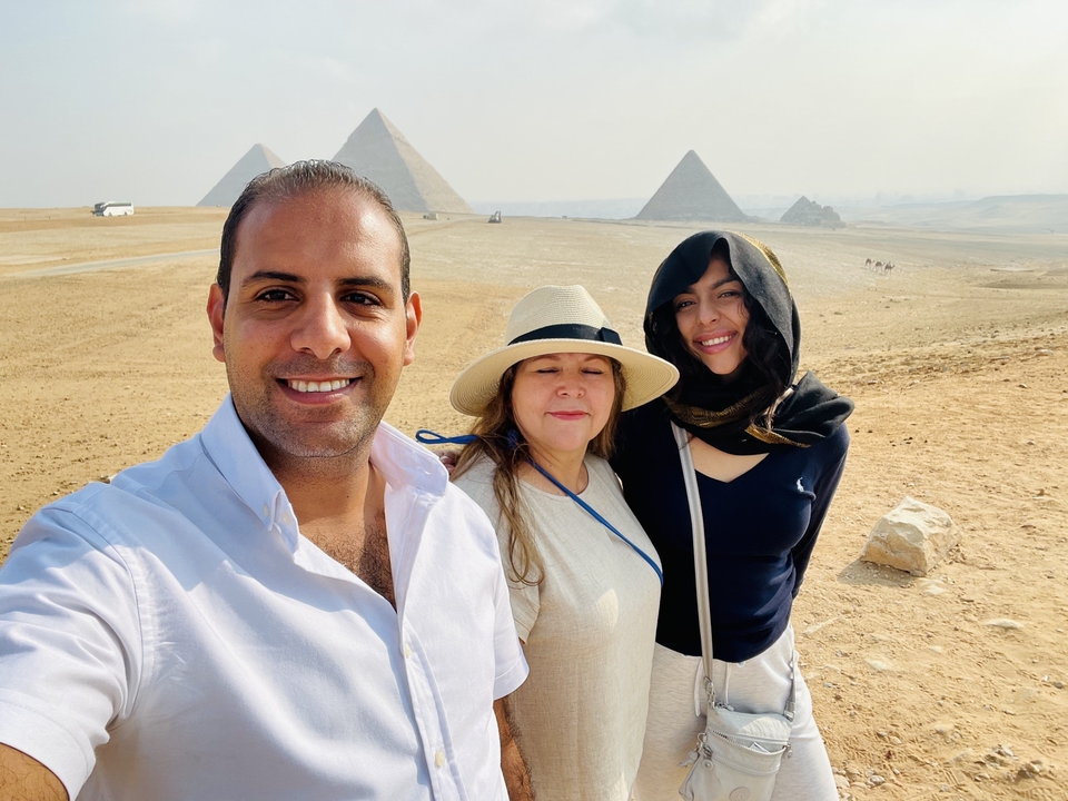 Selfie avec trois personnes et des pyramides en arrière-plan.