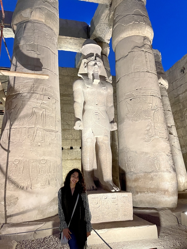 Personne debout à côté d'une statue égyptienne antique massive.