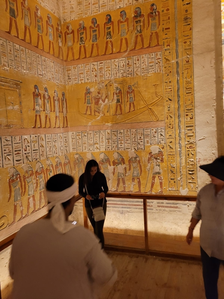 Mur historique avec art égyptien antique et personnes qui observent.