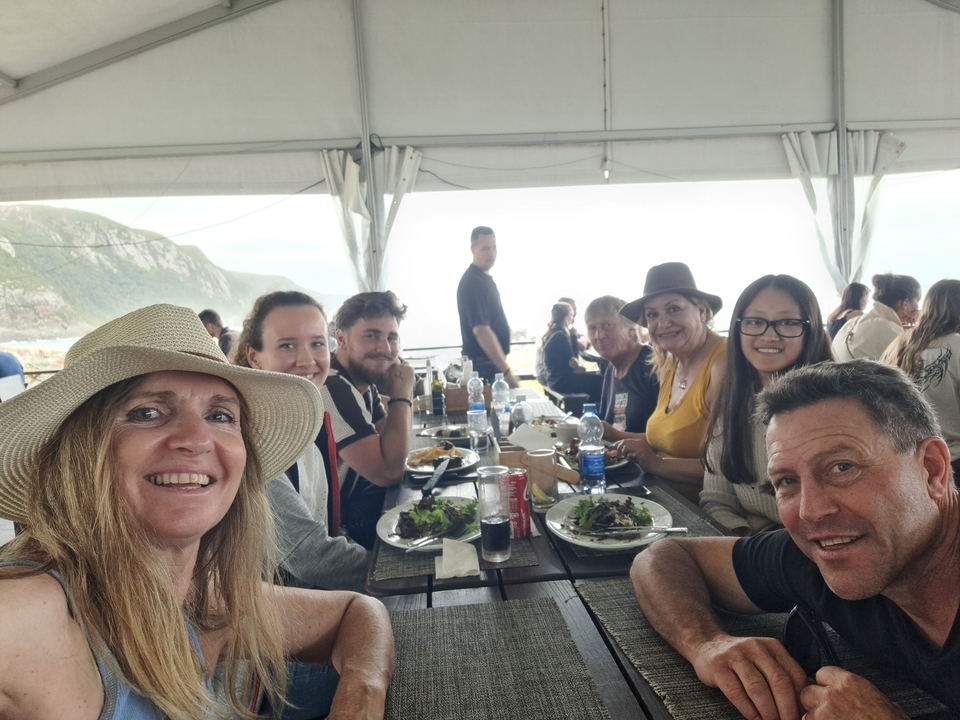 Group dining under a canopy with an ocean view.