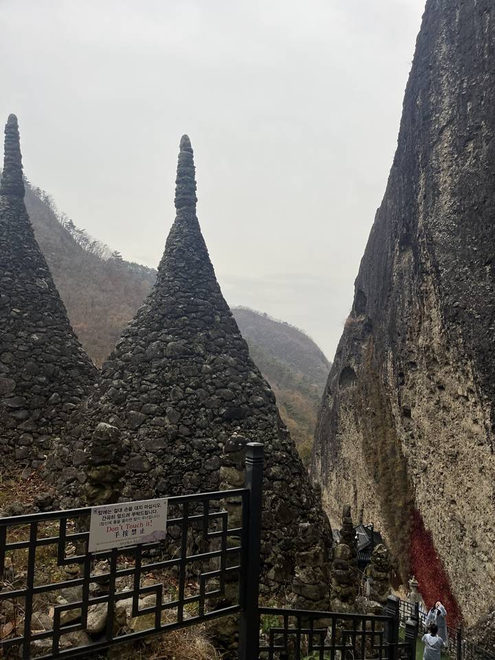 Une structure de pierre unique avec des montagnes en arrière-plan.