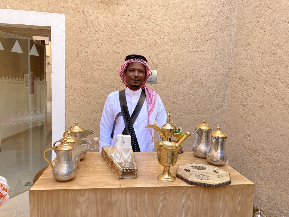 Un homme vêtu d'un costume traditionnel avec un étalage de cafetières.