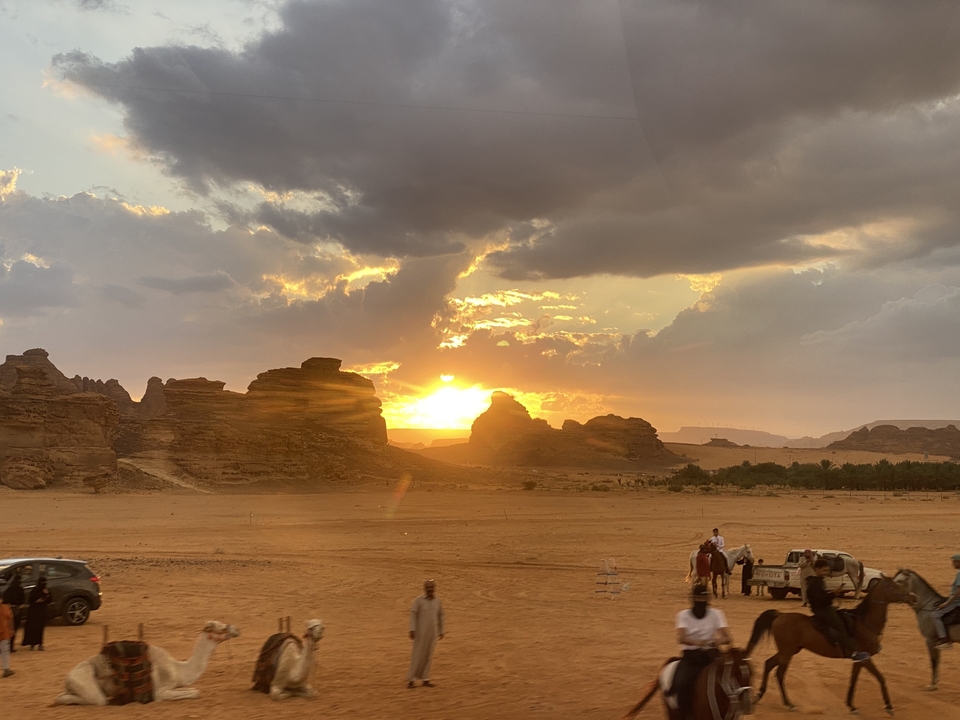 Un paysage désertique avec des personnes et des véhicules au coucher du soleil.